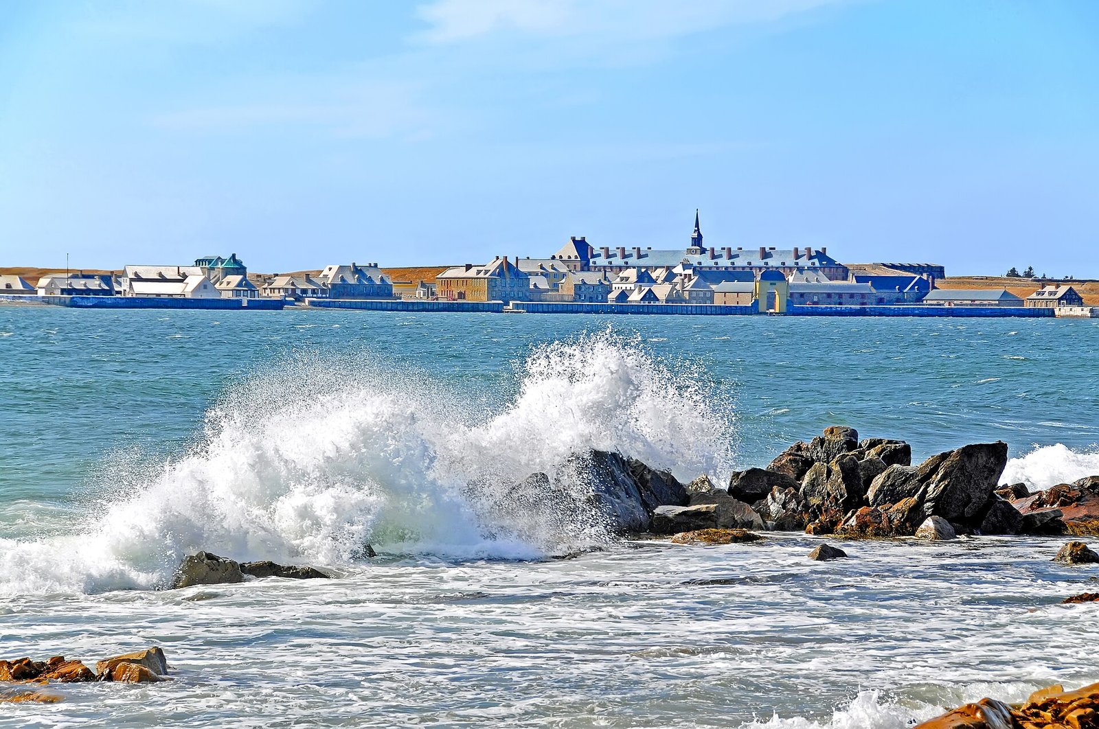 The reconstructed Fortress of Louisbourg seen across the harbor, with waves breaking on rocks
