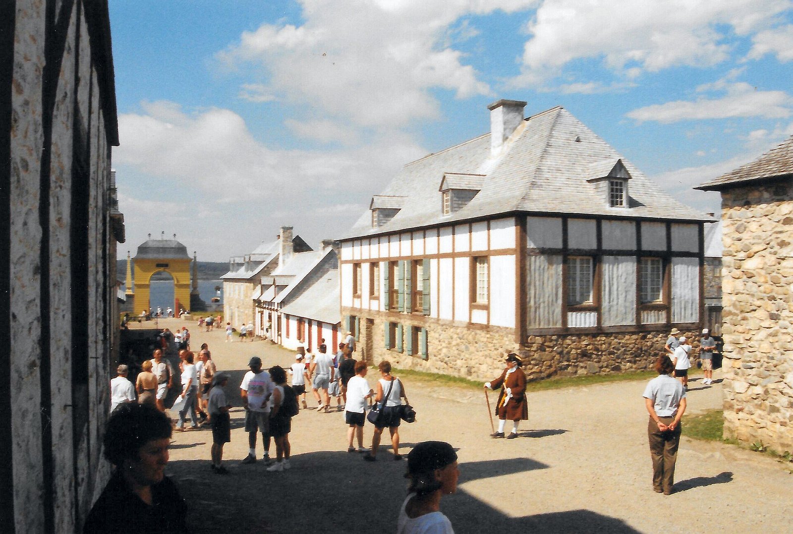 A costumed reenactor in period dress on a street inside the Fortress of Louisbourg